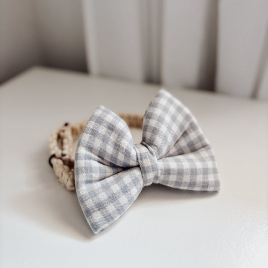 Gray checkered bow tie on a white surface with a neutral background