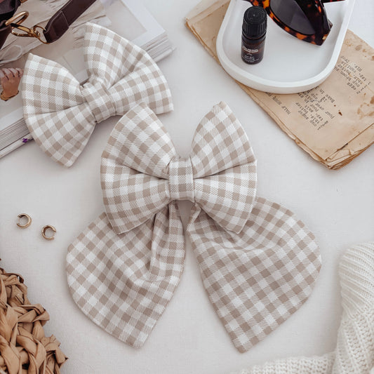 Two gingham checkered bows on a light surface with accessories around.