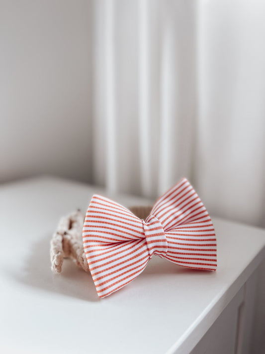 Red and white holiday stripes over the collar dog bow